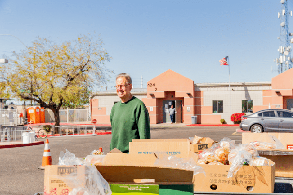 A volunteer standing behind boxes of emergency food bank and donations